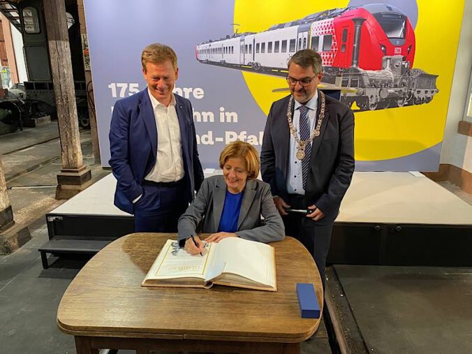 Bahnchef Dr. Richard Lutz und Ministerpräsidentin Malu Dreyer tragen sich ins Goldene Buch der Stadt Neustadt ein. Rechts: Oberbürgermeister Marc Weigel. (Foto: Stadtverwaltung Neustadt)