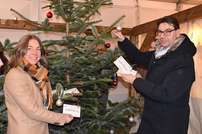 Susanne Burgdörfer vom Haus der Familie und OB Thomas Hirsch hängen die Karten mit den Wünschen an den Kinderwunschbaum. (Quelle: Stadt Landau)