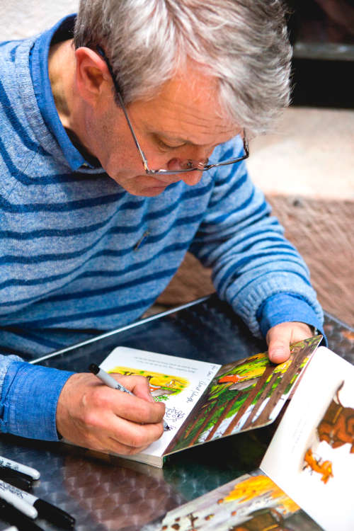 Axel Scheffler signiert Grüffelo-Bücher während seiner Lesung im März 2019 im Historischen Museum der Pfalz. Zur Finissage am 18. Juni 2023 wird er wieder in Speyer erwartet. (Bildnachweis: Foto: Historisches Museum der Pfalz/Carolin Breckle)