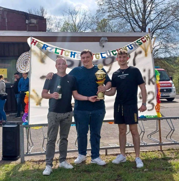 Die Dirigenten der Orchester (links) Peter Kästner, Tim Stilgenbauer, Leon König (rechts) nach der Überraschungssektdusche an der Freizeithalle in Lemberg