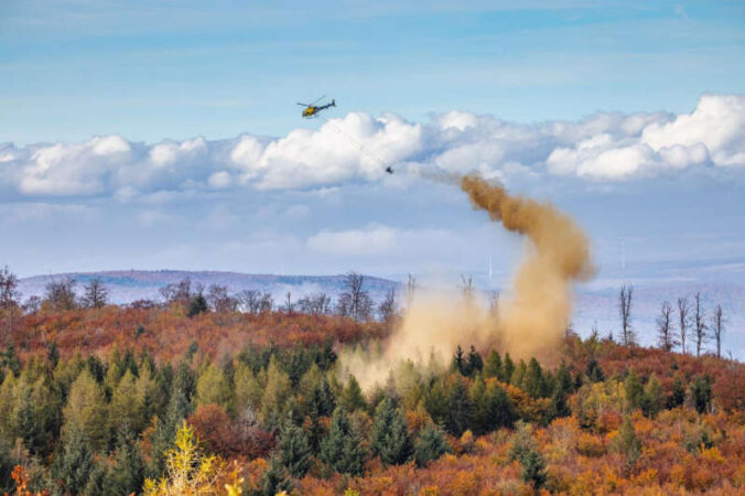 Hubschrauber lässt Kalk über einem Waldgebiet ab. (Foto: Landesforsten.RLP.de / Jonathan Fieber)