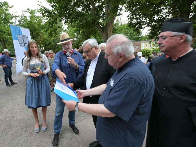 Kirrweilers Bürgermeister Rolf Metzger übergibt den Bischöfen die Urkunde zum diesjährigen Zehntwein. (Foto: Bistum Speyer / Klaus Landry)