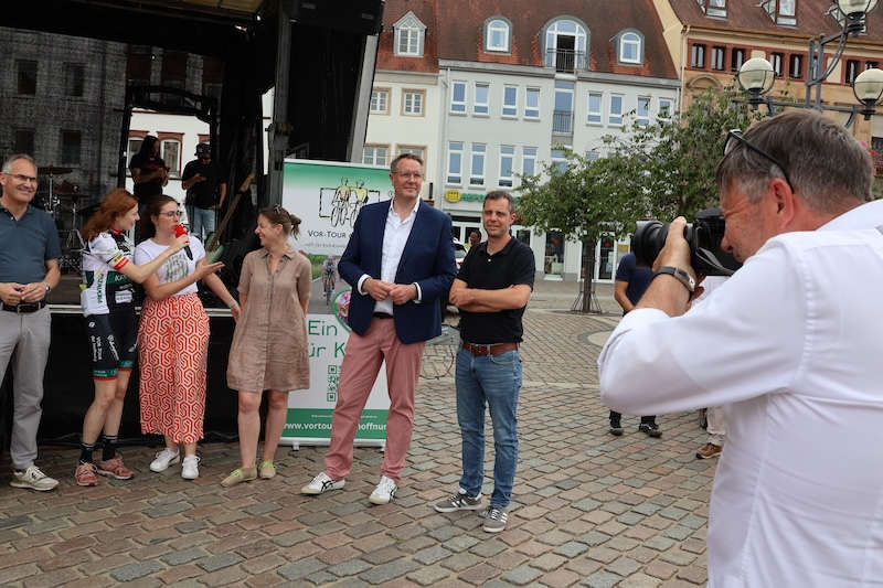 ochrangige Gäste: Dietmar Seefeldt, Landrat des Landkreises Südliche Weinstraße, Juliane Schäfer, deutsche Weinprinzessin und Moderatorin der VOR-Tour der Hoffnung, Lena Dürphold, Beigeordnete der Stadt Landau, Nina Ziegler, Geschäftsführerin des Büros für Tourismus Landau, Ministerpräsident Alexander Schweitzer und Landtagsabgeordneter Florian Maier (v.l.n.r.) nahmen an der Abschlussveranstaltung der VOR-TOUR der Hoffnung teil. (Quelle: Stadt Landau)