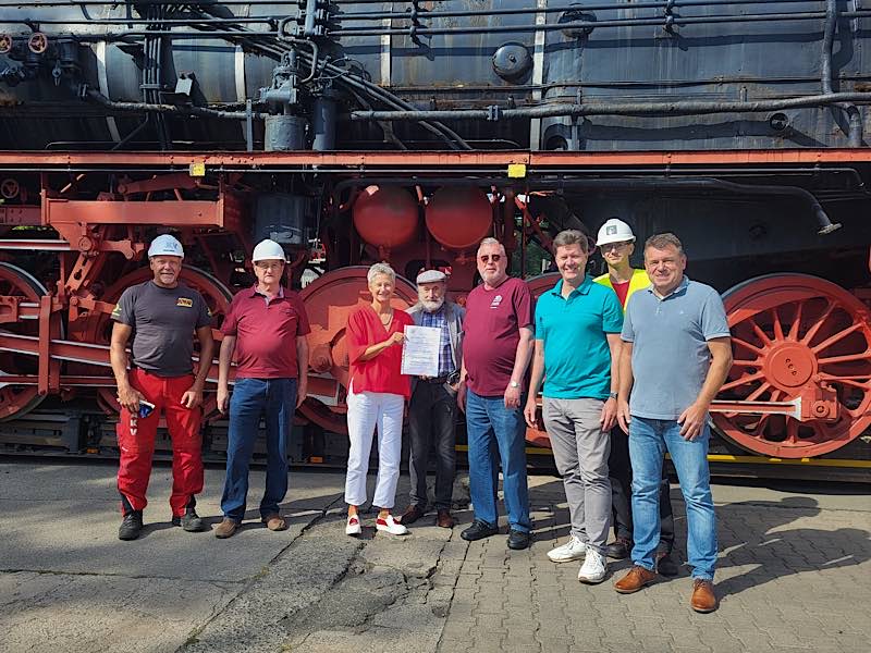 Oberbürgermeisterin Beate Kimmel übergibt den Schenkungsvertrag an Karl-Heinz Ochs, Vorsitzender des Fördervereins „Dampflok am Stellwerk“, (4.v.r.). Mit dabei sind Erfenbachs Ortsvorsteher Paul-Peter Götz (4.v.l.) und Günter Hüther (1.v.l.) sowie weitere Mitglieder des Fördervereins. (Foto: Stadt Kaiserslautern)