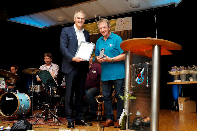 Peter Kusenbach (rechts), unter anderem Leiter des Chors „Herztöne“, der bei „Deutschland singt und klingt“ vertreten war, bekam von Landrat Dietmar Seefeldt die Goldene Wappennadel des Landkreises Südliche Weinstraße überreicht. (Foto: Dieter Hammann)