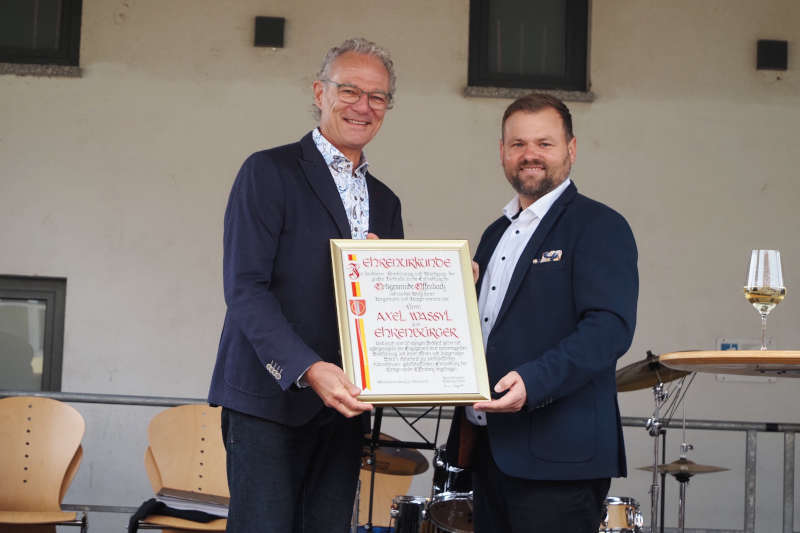 Axel Wassyl (l) bekommtvon Ortsbürgermeister Simon Wingerter die Ehrenbürgerurkunde überreicht. (Foto: Verbandsgemeindeverwaltung Offenbach)