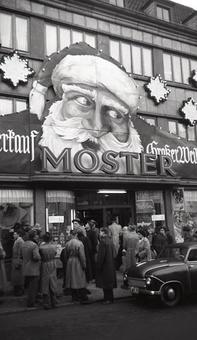 Im Dezember 1954 drängen sich Kunden vor dem Kaufhaus Moster in der Hauptstraße vor der weihnachtlich dekorierten Fassade und den Schaufenstern. (Foto: Sammlung Stadtarchiv Pirmasens)