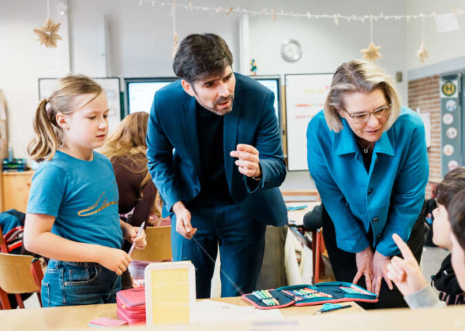 Sven Teuber, Minister für Bildung des Landes Rheinland-Pfalz, und Dr. Katja Scharpwinkel, Vorstandsmitglied der BASF SE und Standortleiterin Ludwigshafen, im Austausch mit Schülerinnen und Schülern der Brüder-Grimm-Grundschule Ludwigshafen. (Foto: BASF/Andreas Henn)