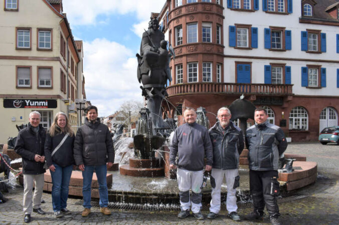 Udo Holzmann, Leiter des Referats Gebäudewirtschaft, Nadine Weber, Abteilungsleiterin Bauausführung und Gebäudeerhaltung, Beigeordneter Manuel Steinbrenner und die Mitarbeiter der Gebäudeerhaltung freuen sich bei schönstem Sonnenschein über den Beginn der Brunnensaison. (Foto: Stadt Kaiserslautern)